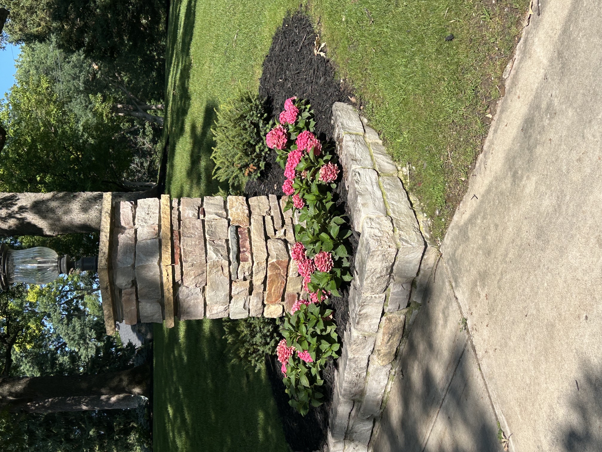The same corner after: stone pillar base rebuilt, stone edging set and a hydrangea bed mulched in
