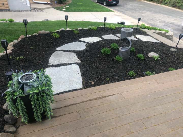 Bed rebuilt with black mulch, flagstone steppers and new plantings beside a driveway