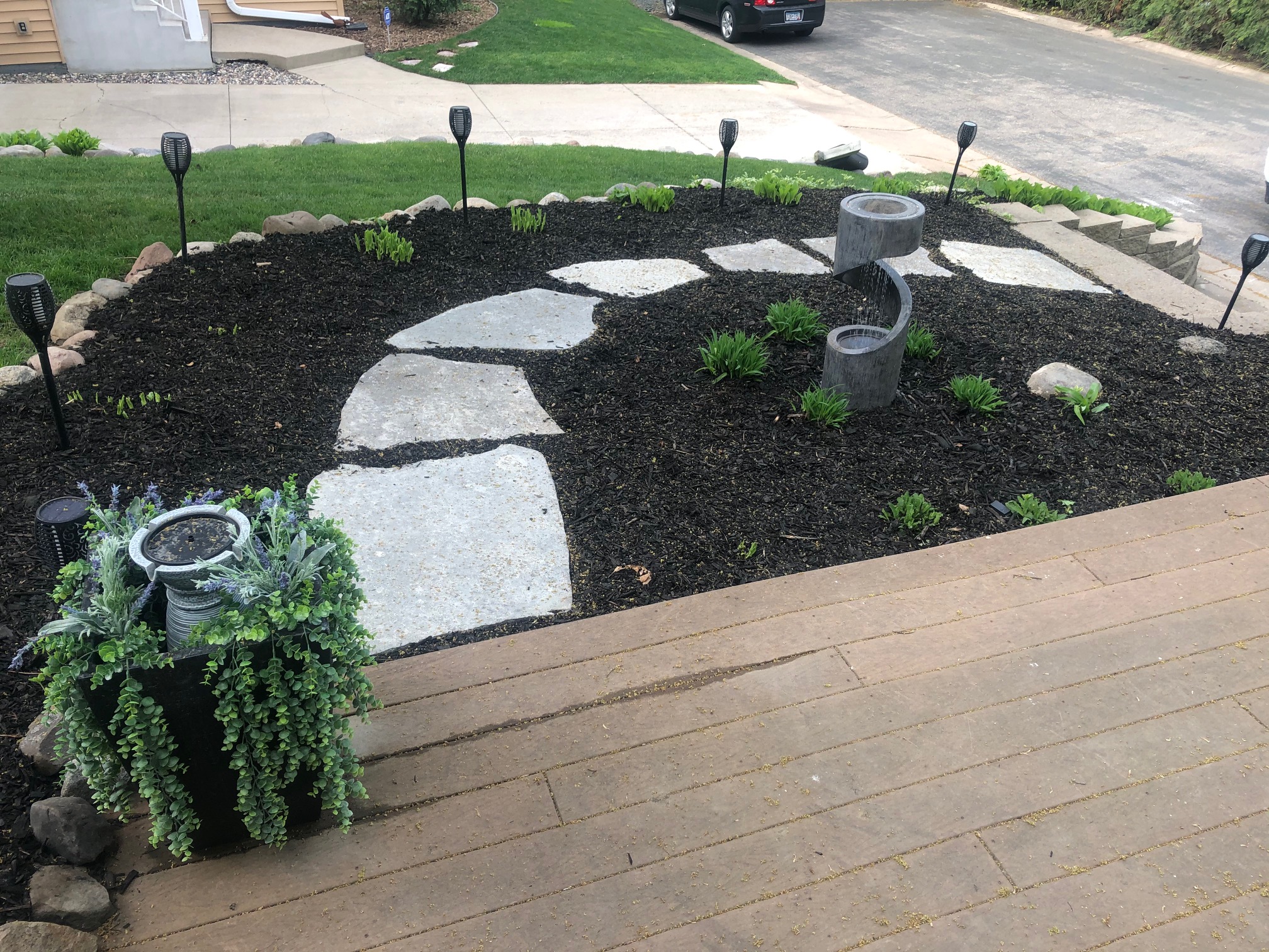 Bed rebuilt with black mulch, flagstone steppers and new plantings beside a driveway