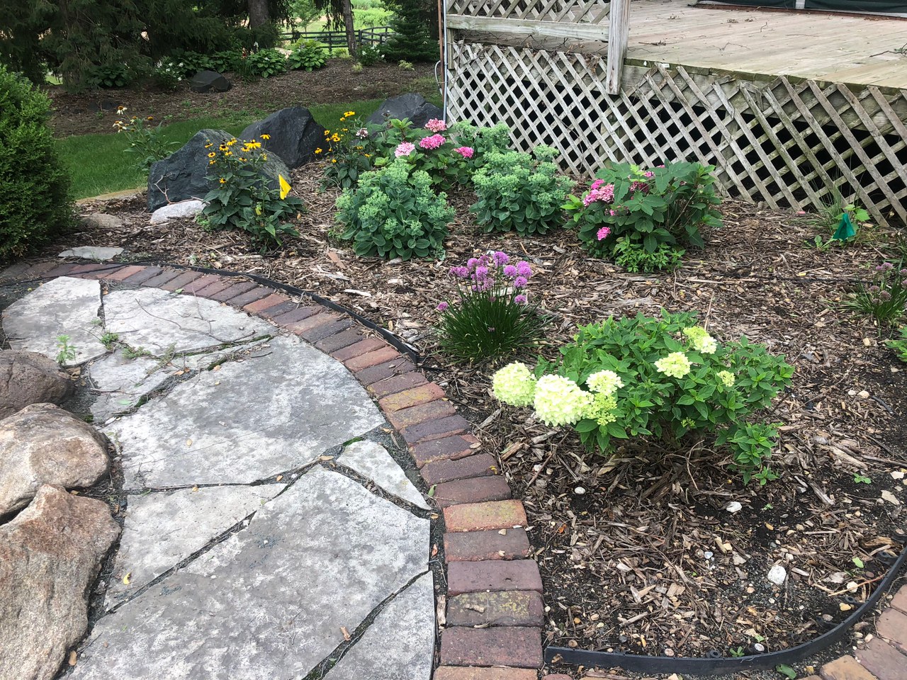 Brick edging running around a flagstone landing next to a planted bed